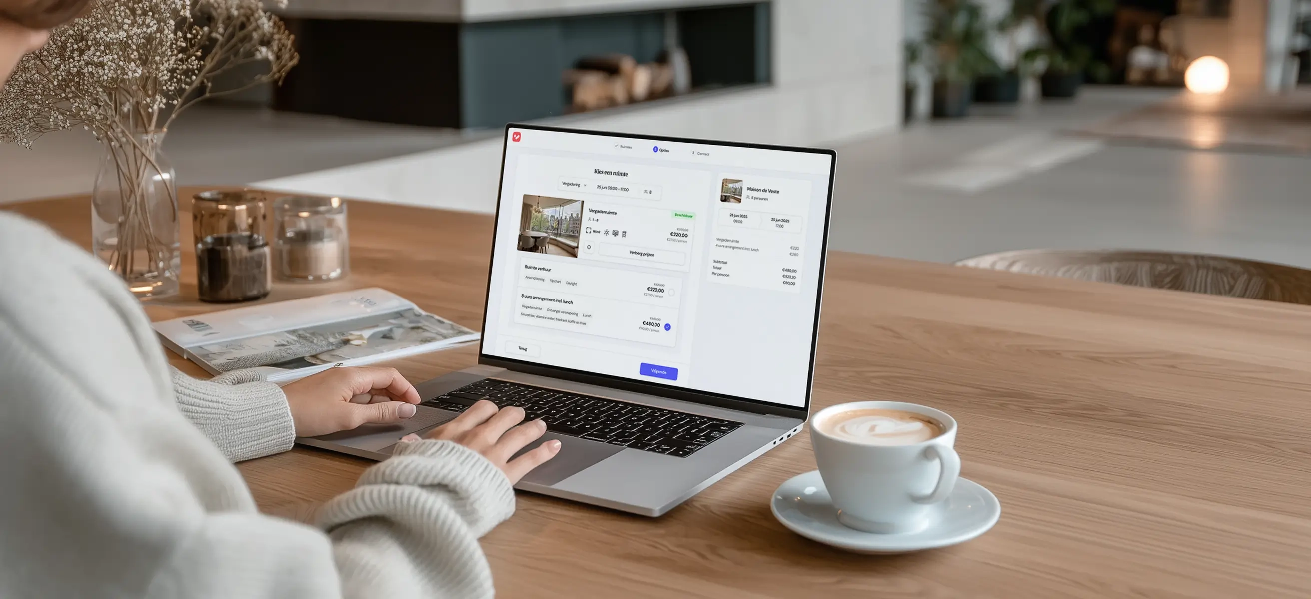 Een venue host zit thuis aan de eettafel met een laptop en een kop koffie. Op het scherm van de laptop staat de VenueSuite software weergegeven.