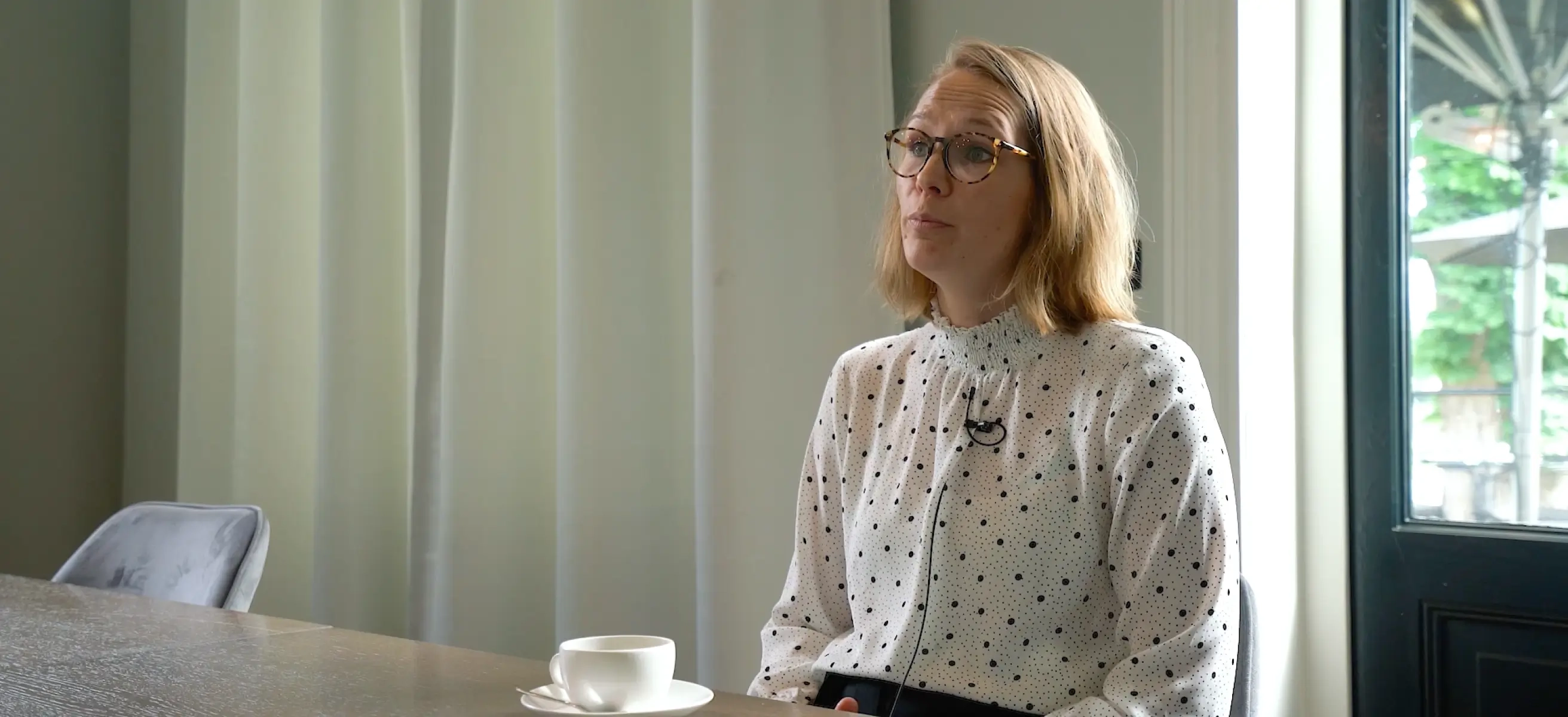 Foto van een vrouw aan een tafel met koffie die wordt geïnterviewd over de VenueSuite booking engine